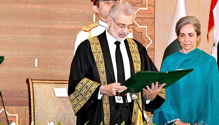 Chief Justice of Pakistan Qazi Faez Isa while taking the oath of office at Aiwan e Sadr with her wife standing alongside him. — NNI/File
