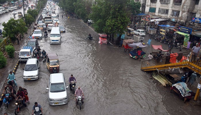 Commuters struggle to move forward in a flooded street after heavy monsoon rains at the University Road in Karachi on July 8, 2022. Photo: ONLINE