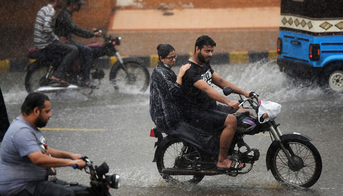 Commuters ride motorbikes along a street during a monsoon rainfall in Karachi on July 5, 2022.-AFP