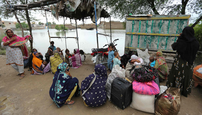 Families sit alongside flood waters after being evacuated following heavy monsoon rainfall in the flood affected area of Rajanpur district in Punjab province on August 24, 2022. —AFP