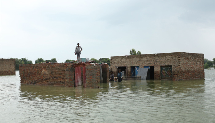 Residents stand around their submerged houses following heavy monsoon rainfall in the flood affected area of Rajanpur district in Punjab province on August 24, 2022.-AFP