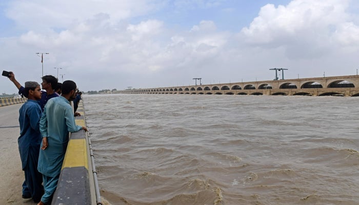 In this picture taken on August 27, 2022, residents watch the river Indus along the Sukkur Barrage in flood hit Sukkur of Sindh province. The fate of hundreds of thousands of people in Sindh lies with a 90-year-old barrage that directs the flow of water from the mighty Indus river into one of the world´s largest irrigation systems. -AFP