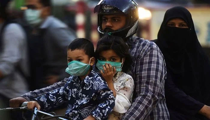 A family riding on a bike wear facemasks as a precaution against the coronavirus on October 29 in Karachi. — AFP/File