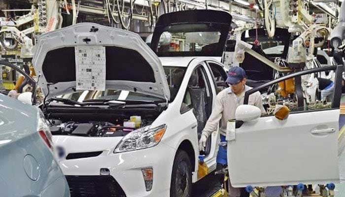 A worker is fixing gate of a car at an auto manufacturing unit. — AFP/File