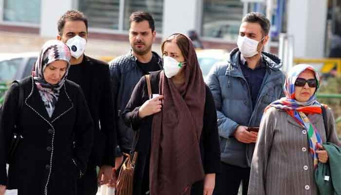 Iranians, some wearing protective masks, wait to cross a street in the capital Tehran on February 22, 2020. — AFP/Files