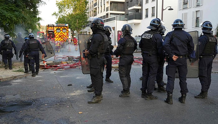 Police in riot gear stand guard as firefighters work to put out fires after a demonstration in Nanterre, west of Paris, on June 27, 2023. — AFP/File