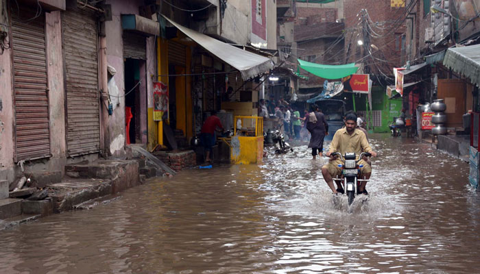 Man seen driving his motorbike on a road deluged by rainwater near Bibi Pakdaman shrine on July 5, 2023. PPI