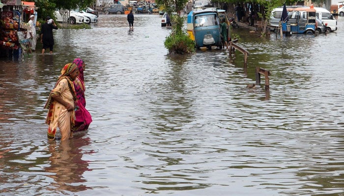 Women pass through accumulated rain water near Hyderabad Railway Station on July 25, 2023. — INP