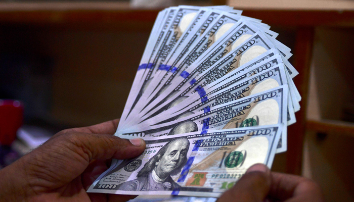 A foreign currency dealer counts US dollar notes at a currency market in Karachi on July 19, 2022. — AFP