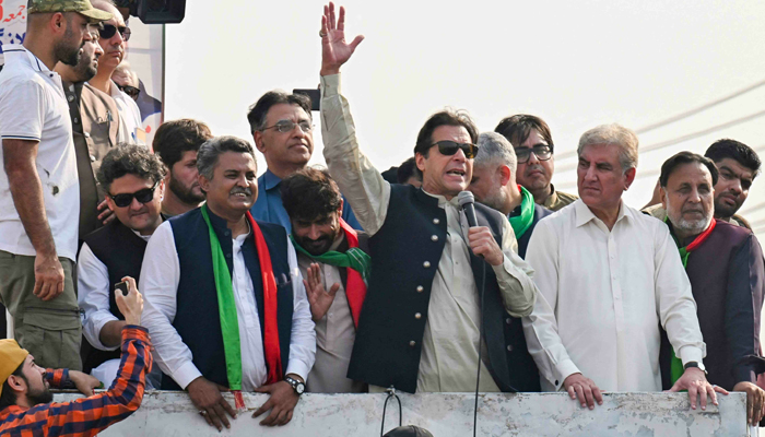 Imran Khan (C) addresses his supporters with leaders including Shah Mehmood Qureshi (right) standing with him during a long march towards Islamabad, in Lahore on October 29, 2022. — AFP
