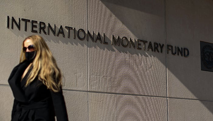 This photo taken on April 05, 2021, shows a woman walking past an International Monetary Fund headquarters (IMF) building in Washington, DC. — AFP