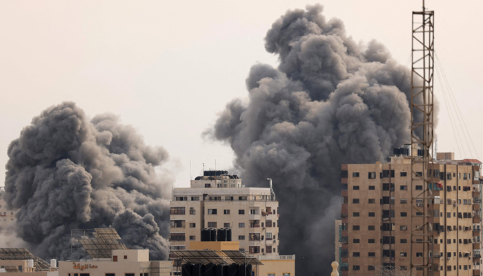 A black plume of smoke billows behind highrise buildings in the sky during an Israeli airstrike on Gaza City on October 9, 2023. — AFP