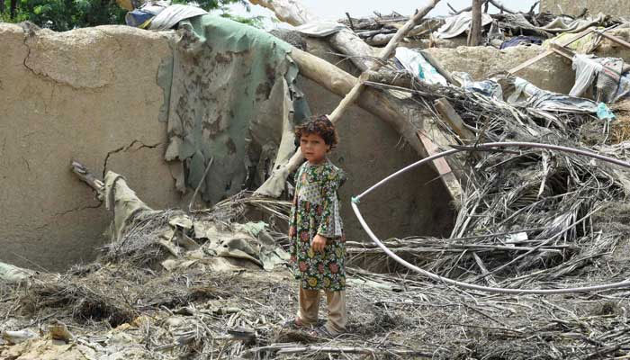 A girl stands over the debris of a damaged mud house at a flood affected town called Gandawah in Jhal Magsi district, Balochistan, on August 2, 2022. — AFP