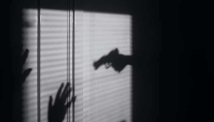 A representational image of a shadow showing a gun and hands. — Unsplash/File