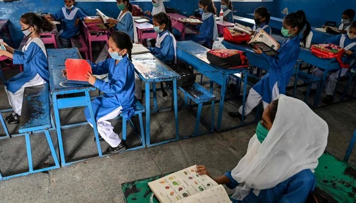 hildren wearing facemasks attend a class at a school in Lahore. — AFP/File