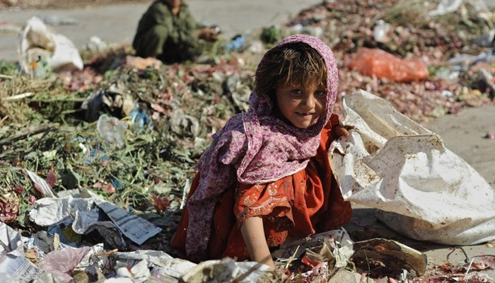 A child can be seen looking on with a smile while sitting on a garbage. — AFP/File