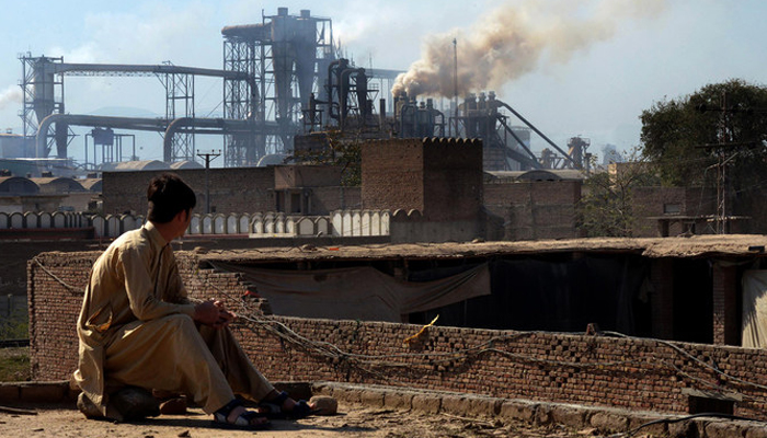 This photo shows a Pakistani worker watching smoke rising from factories on the outskirts of the of Peshawar. — AFP/File