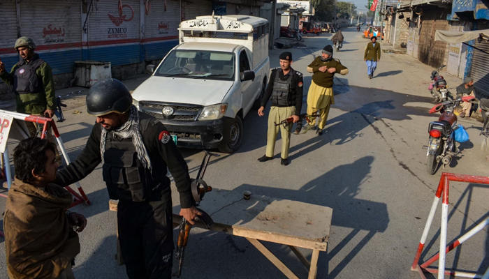 Police officials while checking civilians in KP. — AFP/File
