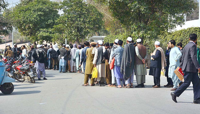 Afghan refugees waiting in a long queue for their turn to apply for passports on Mall road leading to Afghan Commisionerate on February 20, 2023. — APP