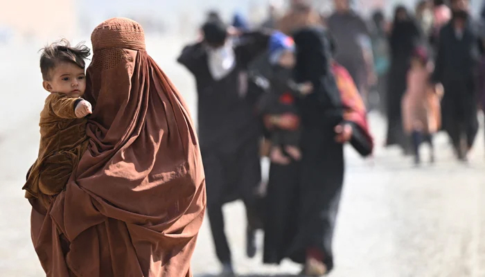 Afghan refugee families arrive on foot to cross the Pakistan-Afghanistan Torkham border on November 2, 2023. — AFP