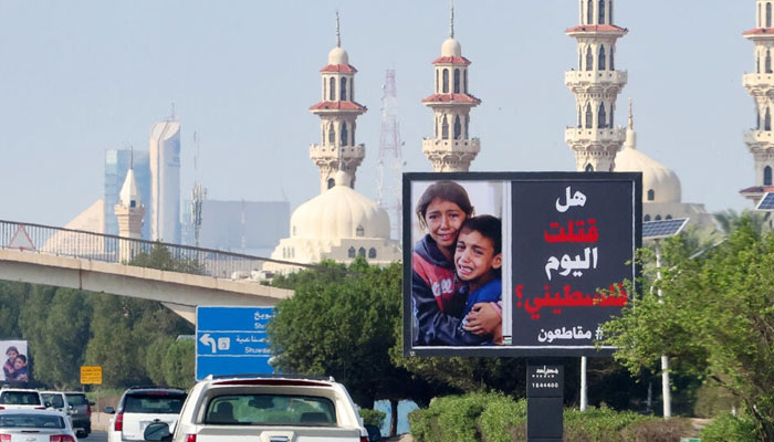 Cars drive past a billboard in Kuwait City showing Palestinian children and the slogan: Have you killed a Palestinian today?. — AFP