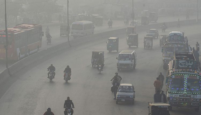 Commuters commute amid heavy smoke in Lahore. — AFP/File