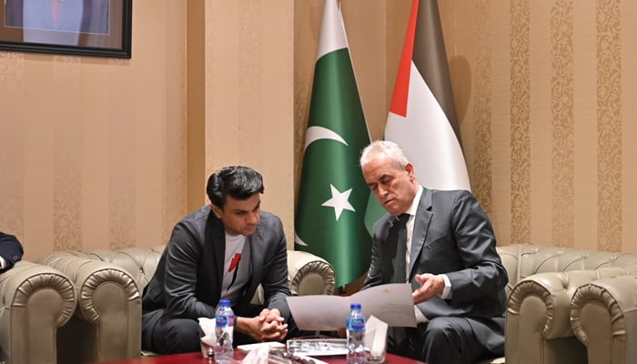 Special Assistant to the Prime Minister on Overseas Pakistanis and Human Resource Development Jawad Sohrab Malik looks towards a paper being shown by the Palestinian Envoy Ahmed Rabi’i in Islamabad on November 9, 2023. — X/@JawadSohrab