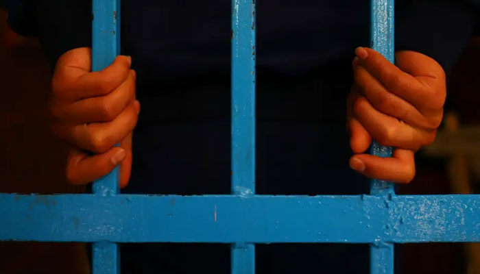 Representational image of a person behind bars. — AFP/File