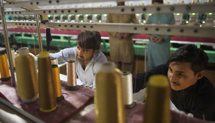 This file photo, taken on September 2, 2020, shows workers supervising embroidery machines working on fabrics for wedding dresses at a small factory on the outskirts of Islamabad. — AFP/File