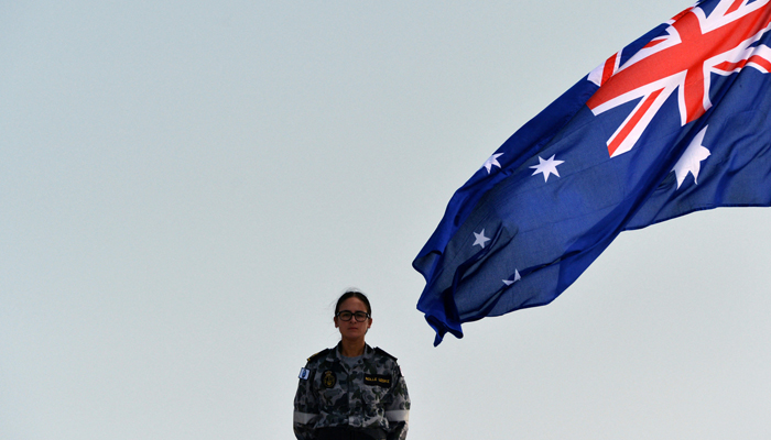 A Royal Australian Navy personnel stands next to Australias flag as she takes part in a training exercise. — AFP/File