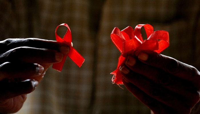 An HIV-positive person from the Support and Care Centre of the Sumanahalli Society prepares red ribbons on the eve of World Aids Day in Bangalore on November 30, 2015. —AFP File