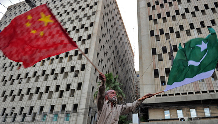 A man waves Pakistani (R) and Chinese national flags on a street in Karachi. — AFP/File