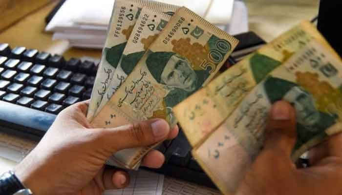 A money trader counts Rs500 bank currency notes at a money exchanger. — AFP/File