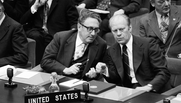 US Secretary of State Henry Kissinger (L) speaks with US President Gerald Ford during the OTAN summit in Brussels on May 30, 1975. — AFP