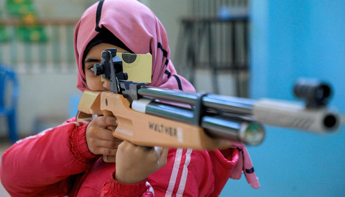 A woman athlete looks through the scope of an air rifle while competing in a local shooting championship on January 3, 2023.— AFP