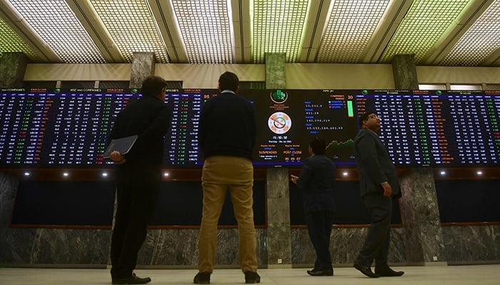 Brokers monitor an index board showing the latest share prices at the PSX in Karachi. — AFP/File