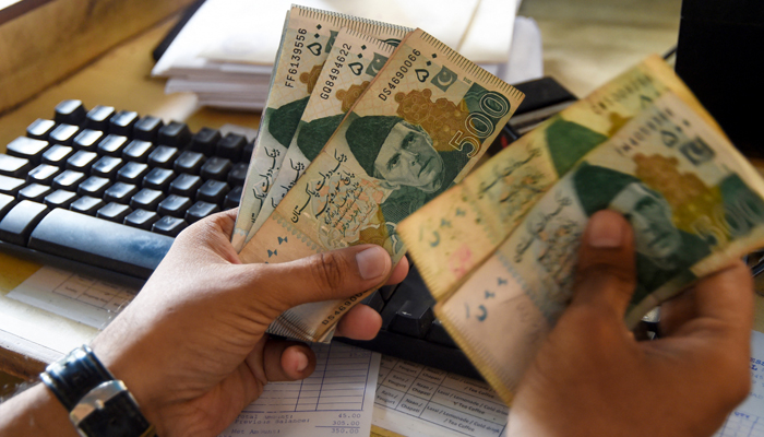 A man counts rupees at his shop in Karachi. — AFP/File