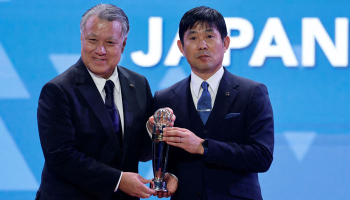 Japans national team coach Hajime Moriyasu (R) is presented with the AFC Coach of the Year during the AFC Annual Awards Doha 2022 on October 31, 2023. — AFP