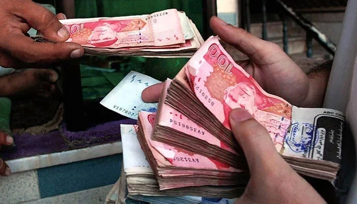 Representational image of a person holding bundles of Pakistani rupee. — AFP/File