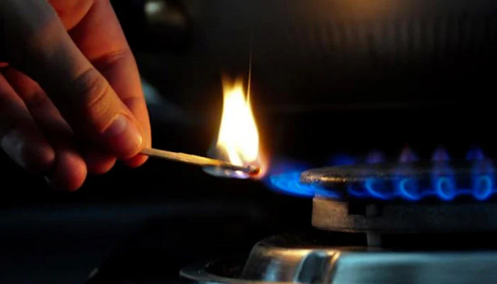 This image shows a person lighting up the flame on a stove using a match. — AFP/File