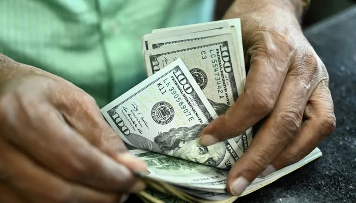 A man counts US dollars in a money exchange shop in Dhaka. — AFP/File