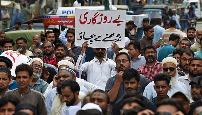 A trader holds a placard reading prevent unemployment from rising during a protest at a street in Karachi on August 23, 2023. — AFP