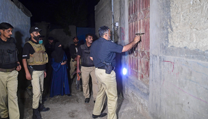 Police personnel conduct a late-night search operation in the outskirts of Karachi on November 11, 2023. — AFP