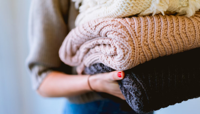 This representational image shows a person holding some warm clothes. — Unsplash/File