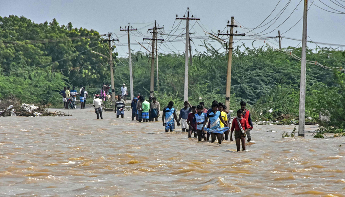 People wade through a flooded road after heavy rains in Thoothukudi on December 20, 2023. — AFP