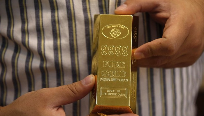 This representational image shows a person holding a gold bar. — AFP/File