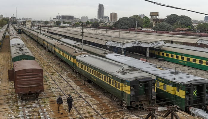Policemen walk along trains stationed on a deserted platform at Karachi Cantonment railway station. — AFP/File