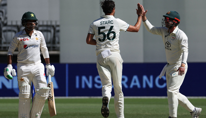 Australias Mitchell Starc (C) celebrates with Travis Head after taking the wicket of Pakistans Sarfaraz Ahmed (L) on day four of the first Test cricket match between Australia and Pakistan in Perth on December 17, 2023. — AFP