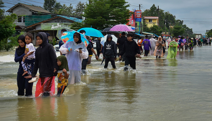 People wade through floodwaters following heavy rain in Thailands southern province of Narathiwat on December 25, 2023. — AFP