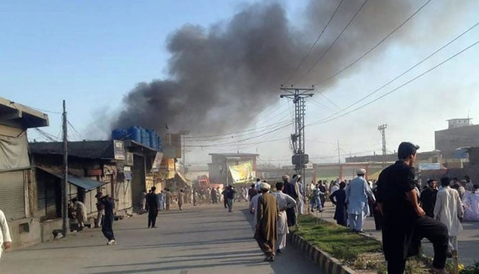 Residents gather along a road as smoke billows after twin blasts at a market in Parachinar, capital of Kurram tribal district. — AFP/File